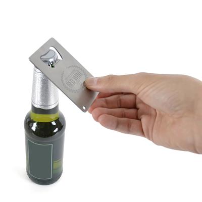 Hand using brushed metal credit card bottle opener to open a glass bottle
